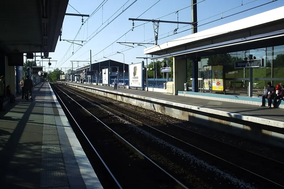 Quai de la gare RER de Bry-sur-Marne, voies ferrées et caténaires sous un ciel bleu, abri vitré sur le quai d'en face