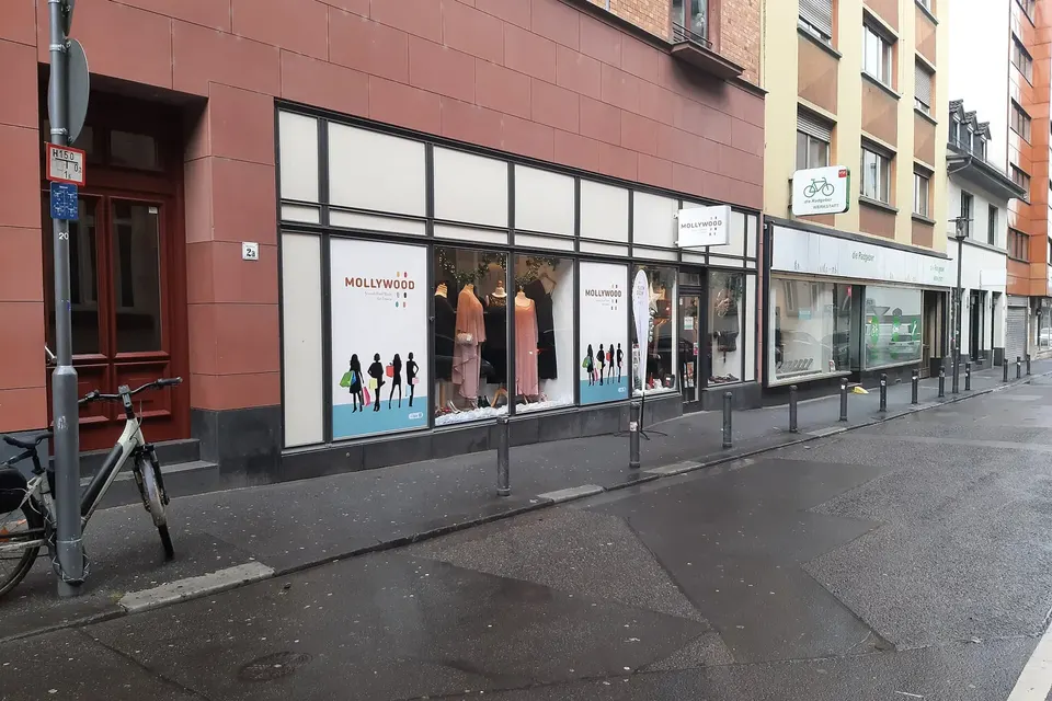Vitrine d'une boutique de vêtements d'occasion au rez-de-chaussée d'un immeuble, dans une rue piétonne pavée