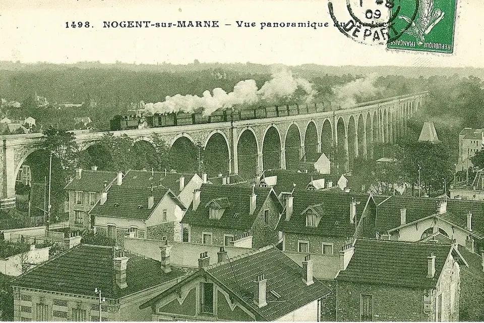 Carte postale ancienne colorisée : un train à vapeur traverse le viaduc de Nogent-sur-Marne au-dessus des toits et des jardins de la ville